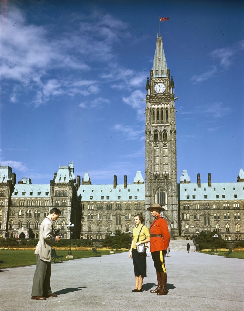 A_member_of_the_RCMP_poses_in_front_of_the_Parliament_Buildings_for_snapshooting_tourists._Ottawa,_Ontario,_Canada
